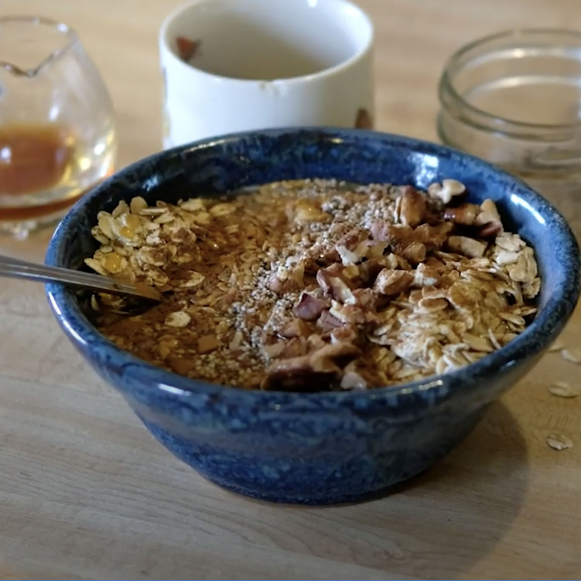 bowl of whole milk yogurt topped with nuts, seeds, and maple syrup 