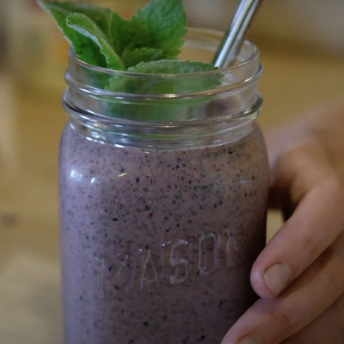 mason jar filled with a purple berry smoothie and garnished with fresh mint