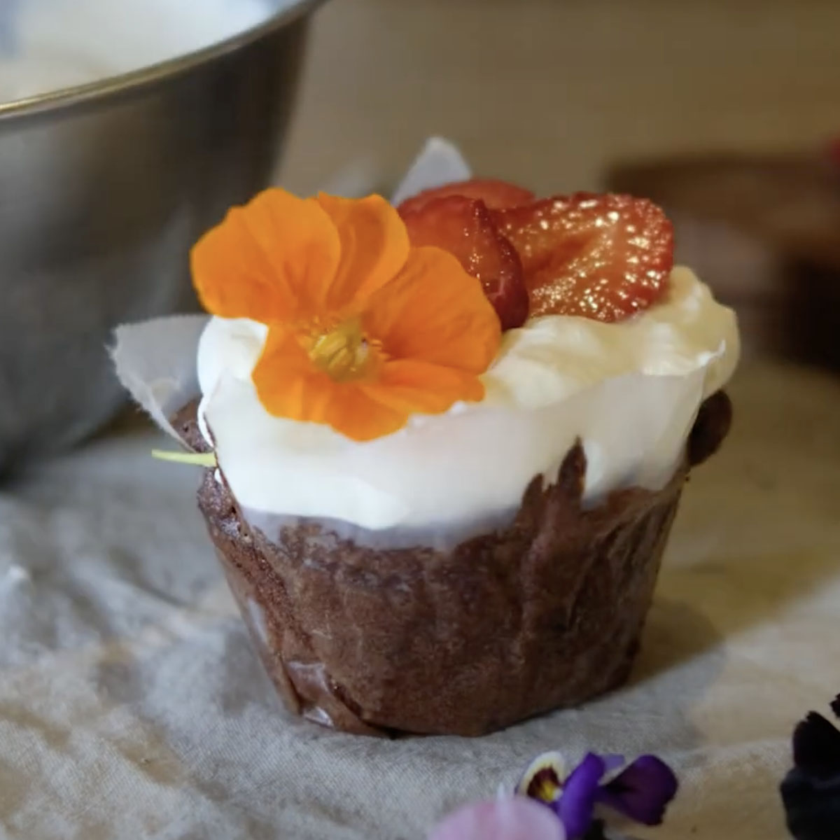chocolate yogurt cupcake topped with whipped cream, strawberries, and edible flowers 